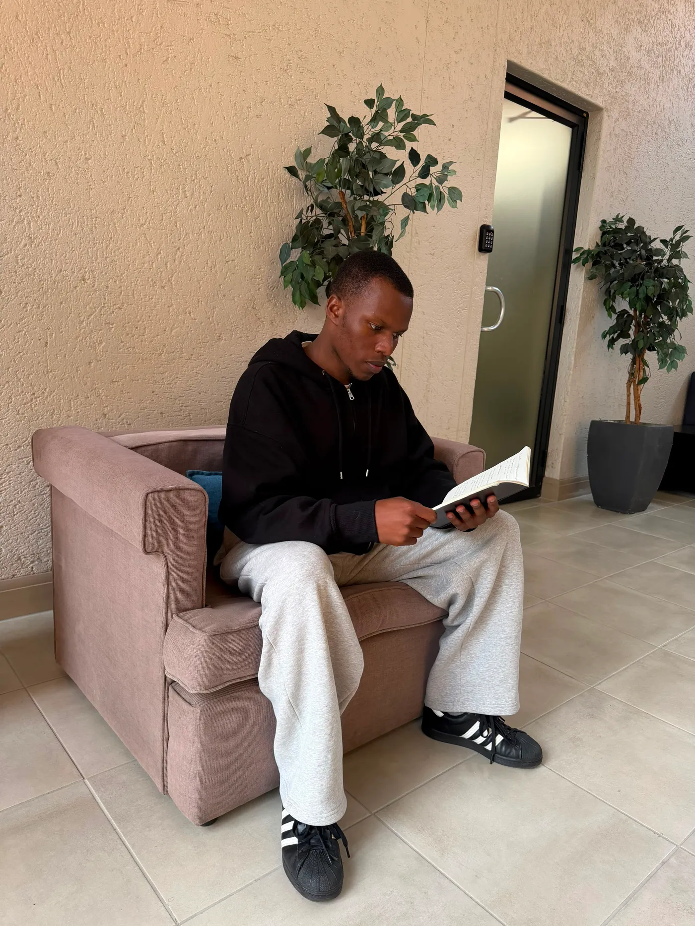 Blessing reading, seen from the side, plants and a doorway behind him